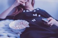 Girl watching tv and eating popcorn