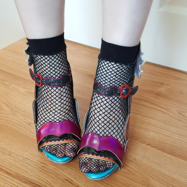 wearing fishnet socks and metallic colourful sandals with open toe and buckle
