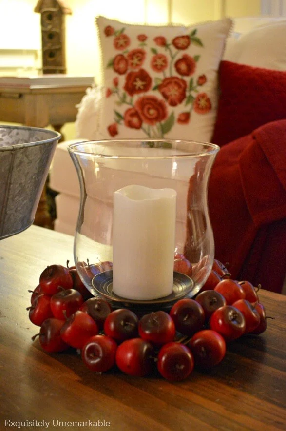 Apple ring around candle and glass hurricane on table in living room