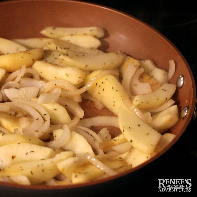 Process shot of skillet with sliced apples and sliced onions with thyme for Pork Loin Filet with Apples and Onions by Renee's Kitchen Adventures