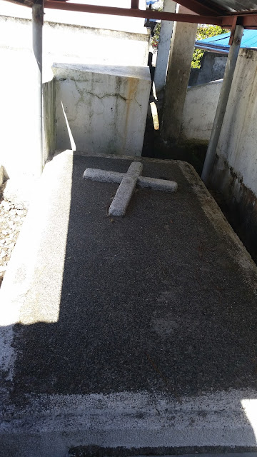 A grey colored tomb with a slant white cross