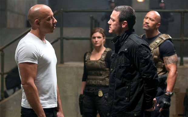 A face-off scene between Dom and the villain Owen Shaw with Hobbs looking on