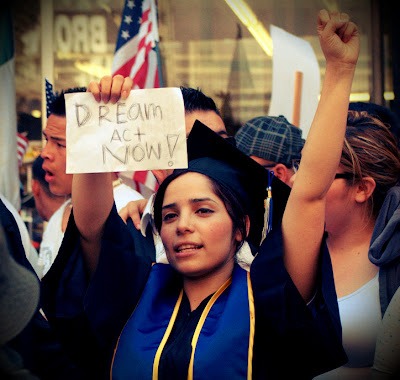 Graduate holds sign reading 'DREAM Act Now!'