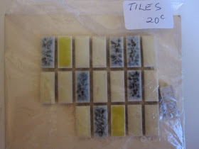 Bag, marked 'tiles 20c', containing 20 vintage dolls house miniature tiles in shades of cream, grey and yellow.