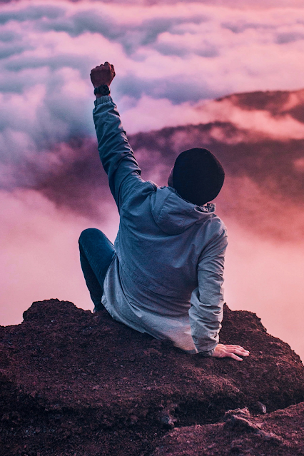 A man enjoying his success atop a cliff.