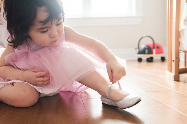 Little girl putting on her party shoes herself before her party. Photo taken during family photo session in Barrahaven, Ottawa Ontario by Melanie Mathieu Photography