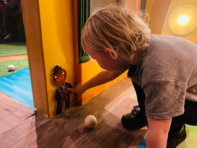 A child pointing at a cut out of a gingerbread man from the gingerbread gang