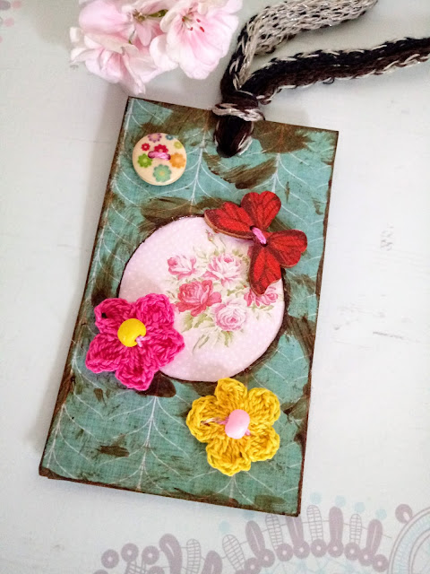 Etiqueta colgante con papel de scrapbooking, florecitas de ganchillo y mariposa de madera