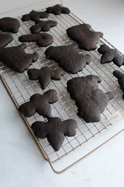 These chocolate cookies have a deep dark color, great chocolate flavor and are perfect for rolling out and cutting into shapes. Your decorated cookie game just went to the next level! black chocolate cut out cookies cooling on wire rack