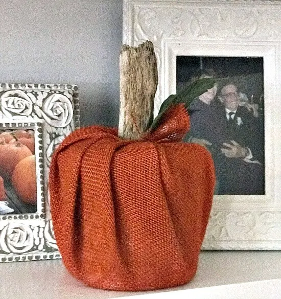 Orange burlap pumpkin on shelf with frames.