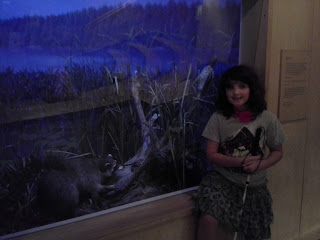 girl withe cane in front of a case with a raccoon. 