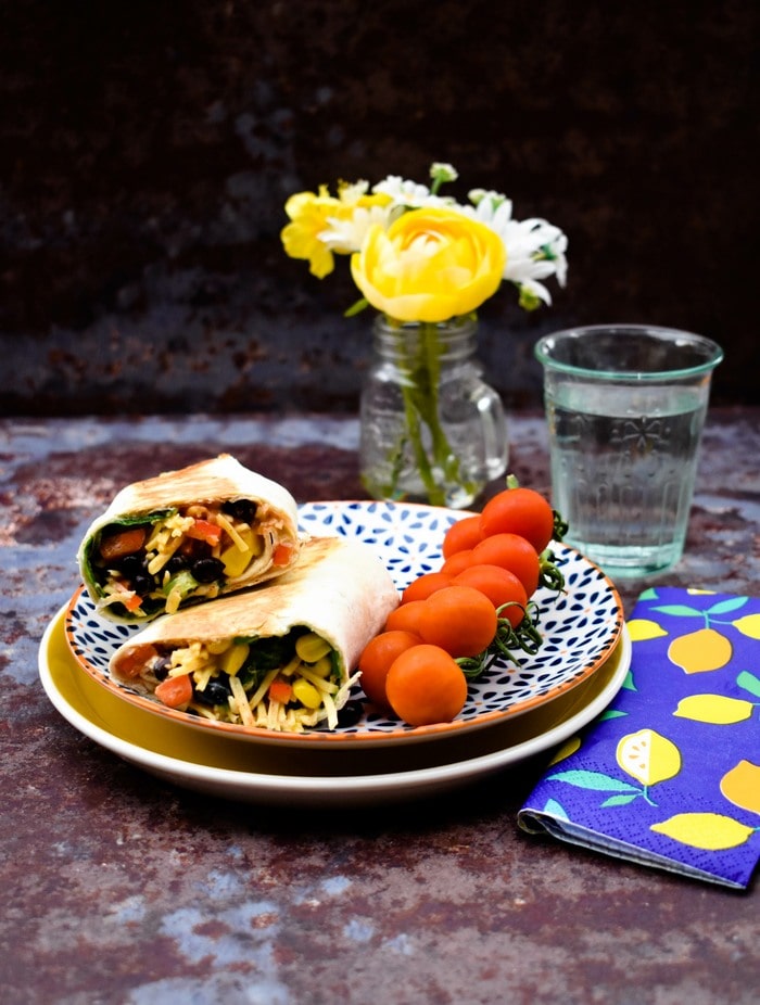 Vegan Tex Mex Cheese Crunch Wrap Tex Mex Cheese Wrap on a yellow plate served with cherry tomatoes and a glass of water