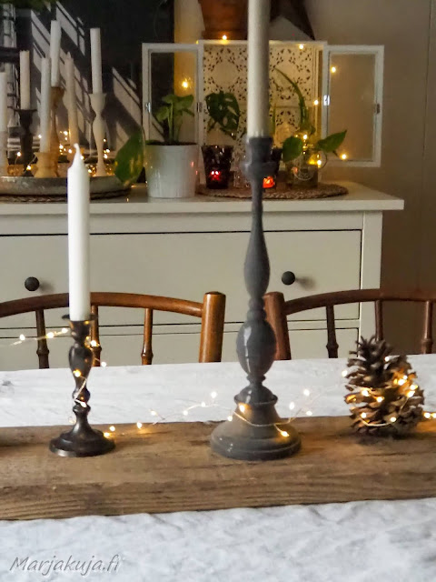 rustiikkinen lankku olohuoneen ruokapöydällä kynttilät, valot ja kävyt koristeena