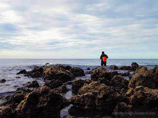 A Man Fishing On The Rocky Beach Seaside In The Evening At The Village Umeanyar North Bali Indonesia