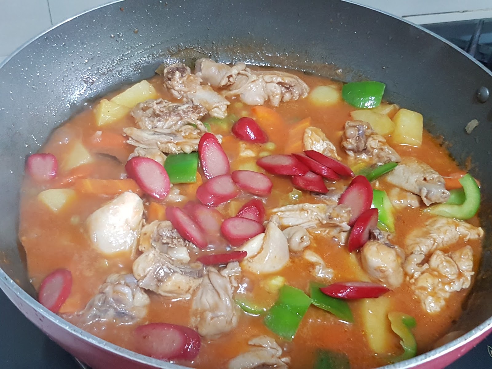 A beautifully plated serving of Chicken Afritada, featuring tender chicken pieces and colorful vegetables in a rich tomato sauce.