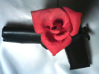 pistol confetionat din piele neagra cu un trandafir rosu din catifea pe tragaci