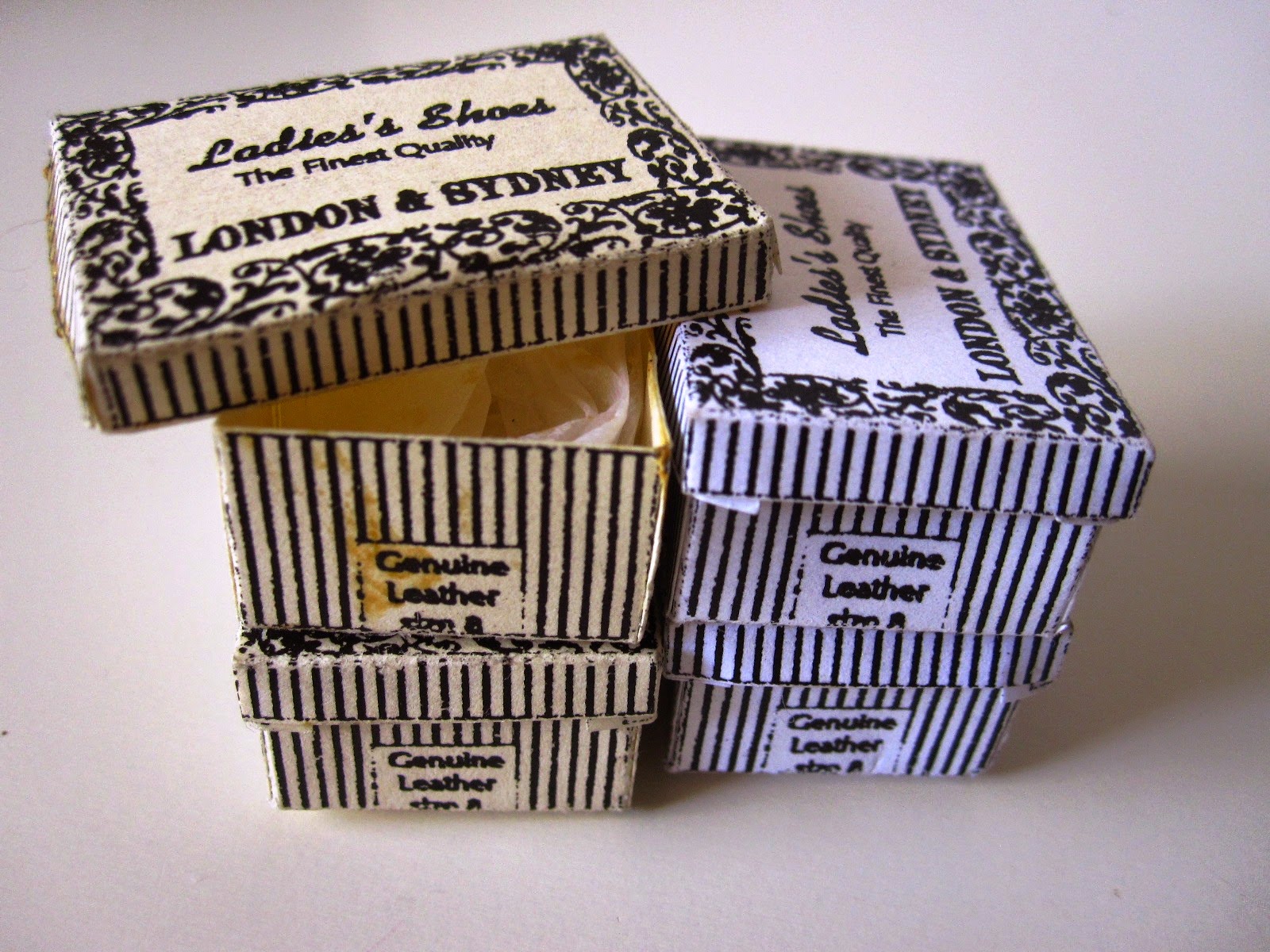 Collection of four miniature vintage black and white striped shoe boxes.