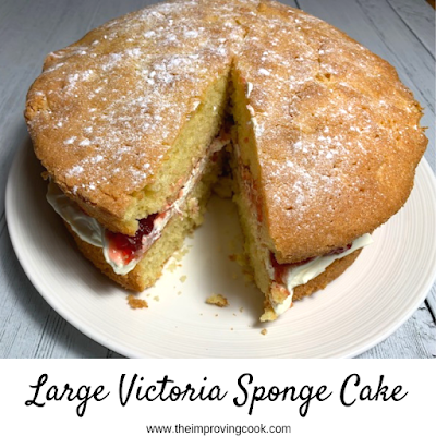 A Victoria Sponge Cake on a white plate with a slice taken out