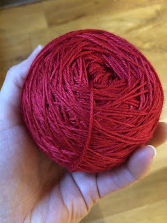 A ball of hand dyed post-box red coloured yarn