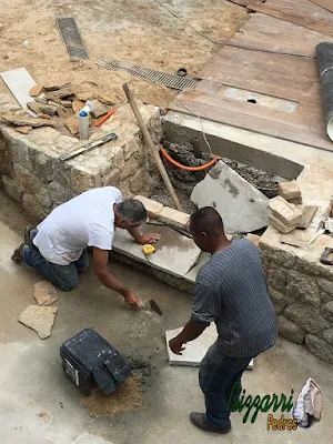 Bizzarri, da Bizzarri Pedras, trabalhando, fazendo a construção da escada de pedra com pedra Carranca sendo tipo cacão nas pisadas da escada e nos espelhos da escada a chapa de pedra moledo no mesmo estilo do muro de pedra.