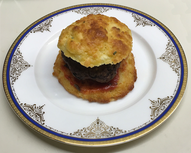 A burger tastes even better on a cheddar cheese and chive biscuit! Photo of hamburger on a biscuit, served on a plate