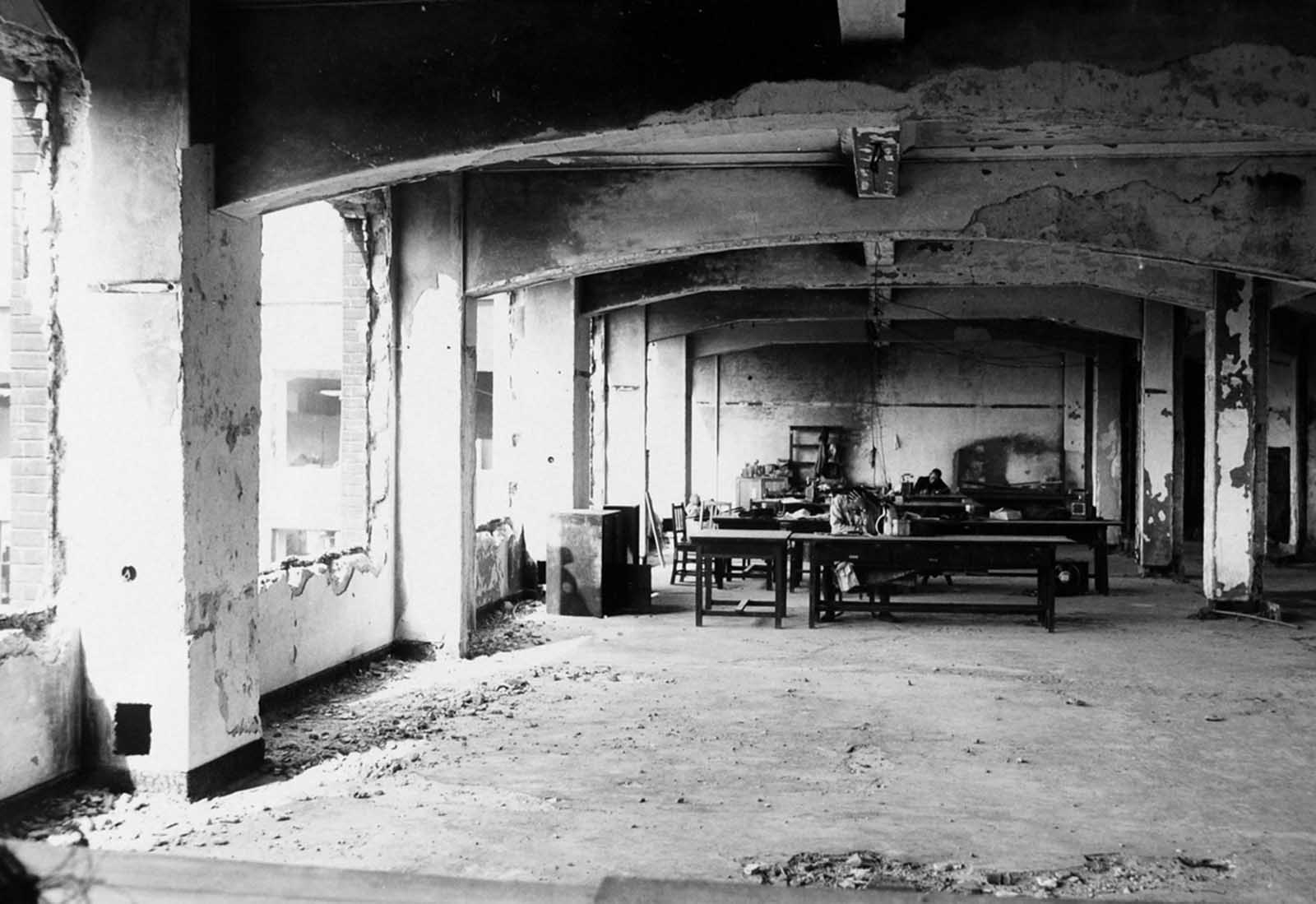 Two Japanese men sit in a makeshift office set up in a ruined building in Hiroshima.