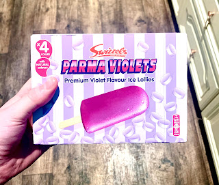 A light purple striped square box containing ice lollies with parma violet ice lollies in light purple font on a bright background