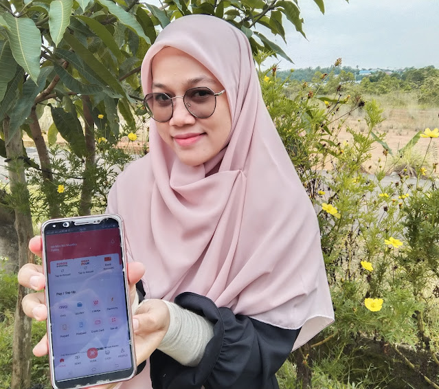 perempuan menunjukkan aplikasi tabungan online simobiplus