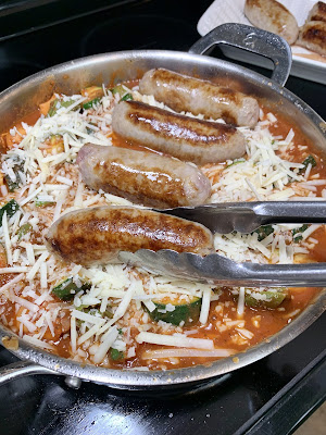 Italian sausages being added to a skillet with red sauce. Italian sausages being added to a skillet with red sauce.