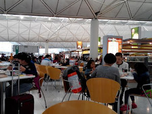 香港機場的美食廣場位於Terminal 1的候機至附近，Food court 一帶有不少桌椅供人使用，亦有時常有職員在清潔收拾，所以很整潔。因為已經過了關，雖然食物一般都較貴，但至少有還算有選擇，比北衞星客運廊那邊好。   相關文章   香港國際機場候機室食物價格 - 早餐篇  ...