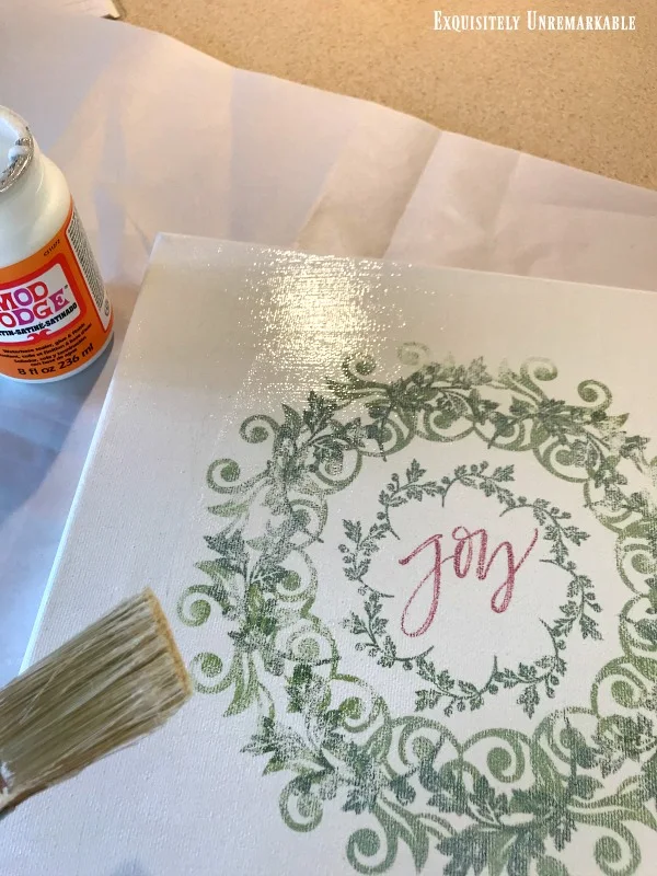 Adding decoupage to canvas with brush over Joy wreath iron on