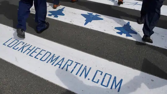 Trade visitors are seen walking over a road crossing covered with Lockheed Martin branding