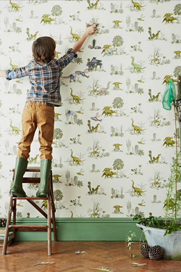 dinosaur magnetic wallpaper with small boy applying magnetized dinos