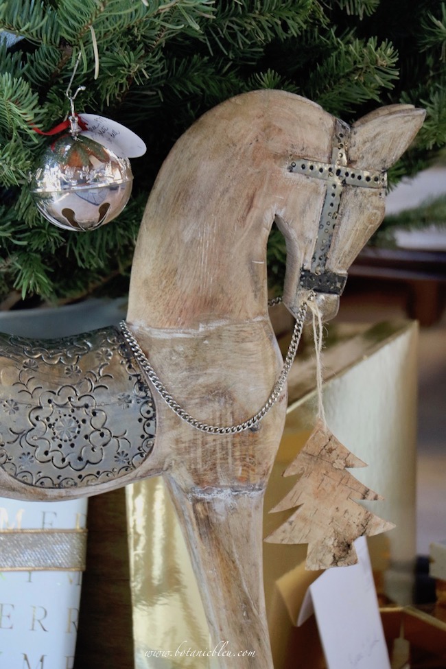 Silver sleigh bell Christmas tree has a hand carved wooden rocking horse