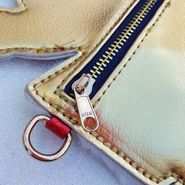 close up of zip opening and D ring on side of handbag