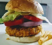 Arranged burger patty and vegetables covered with half of the sesame seeds bun for veg burger recipe