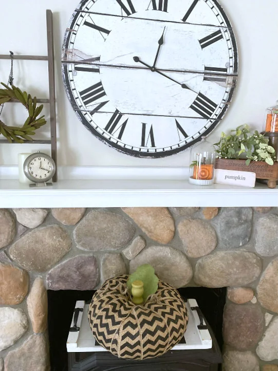 mantel and large clock with chevron pumpkin on the wood burning stove.