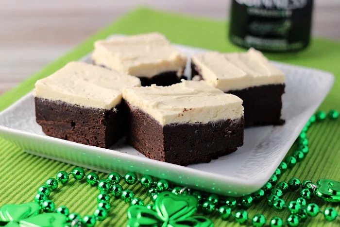 Guinness Brownies with Maple Buttercream Frosting on a white plate with green beads in the foreground  horizontal image