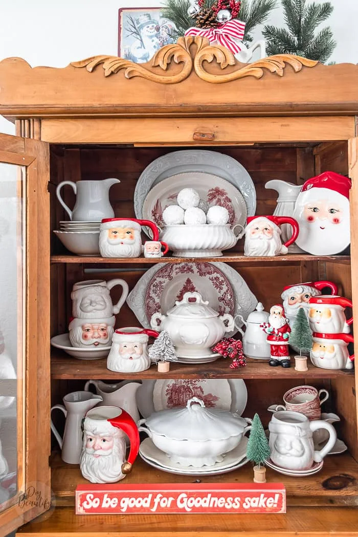 white ironstone, Santa mugs and Christmas dishes fill a pine hutch
