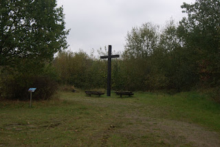 Gipfelkreuz auf einer Wiese, umgeben von Bänken