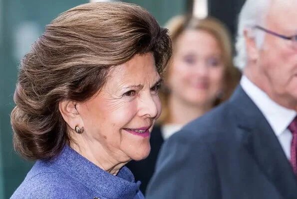 Queen Silvia wore and blue jacket and skirt, skirt suit. She is wearing gold earrings and gold bracelet