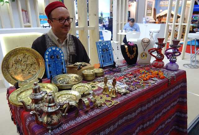 Marokannischer Schmuck auf Tisch mit bunter Tischdecke, Mann in Landestracht auf der f.re.e Reisemesse