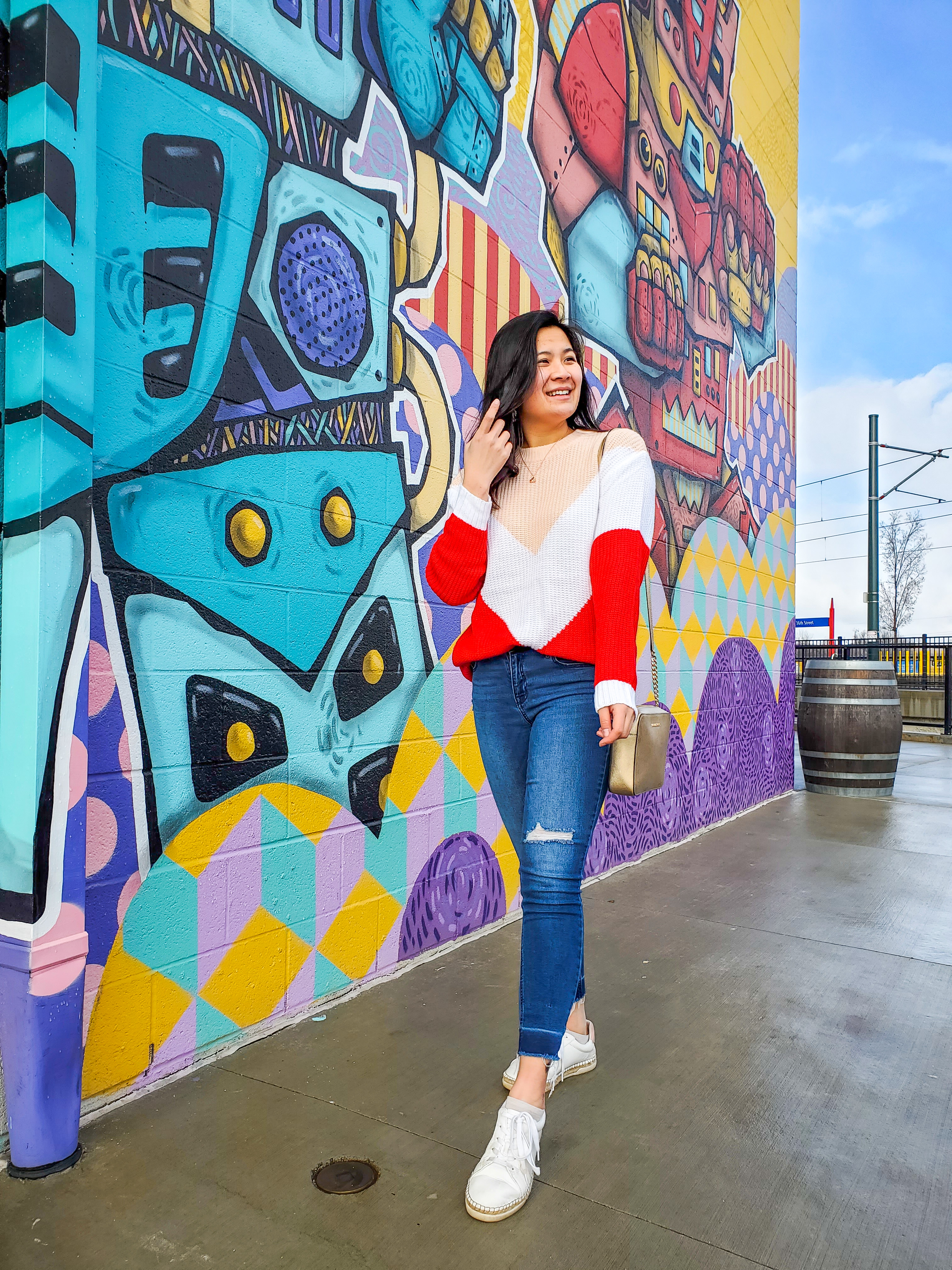 Red and pink color block sweater styled in front of a colorful mural