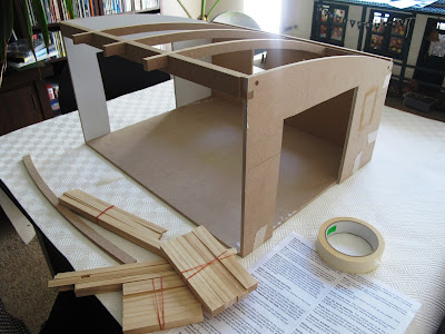 Half-built dolls' house shed sitting on a dining-room table.