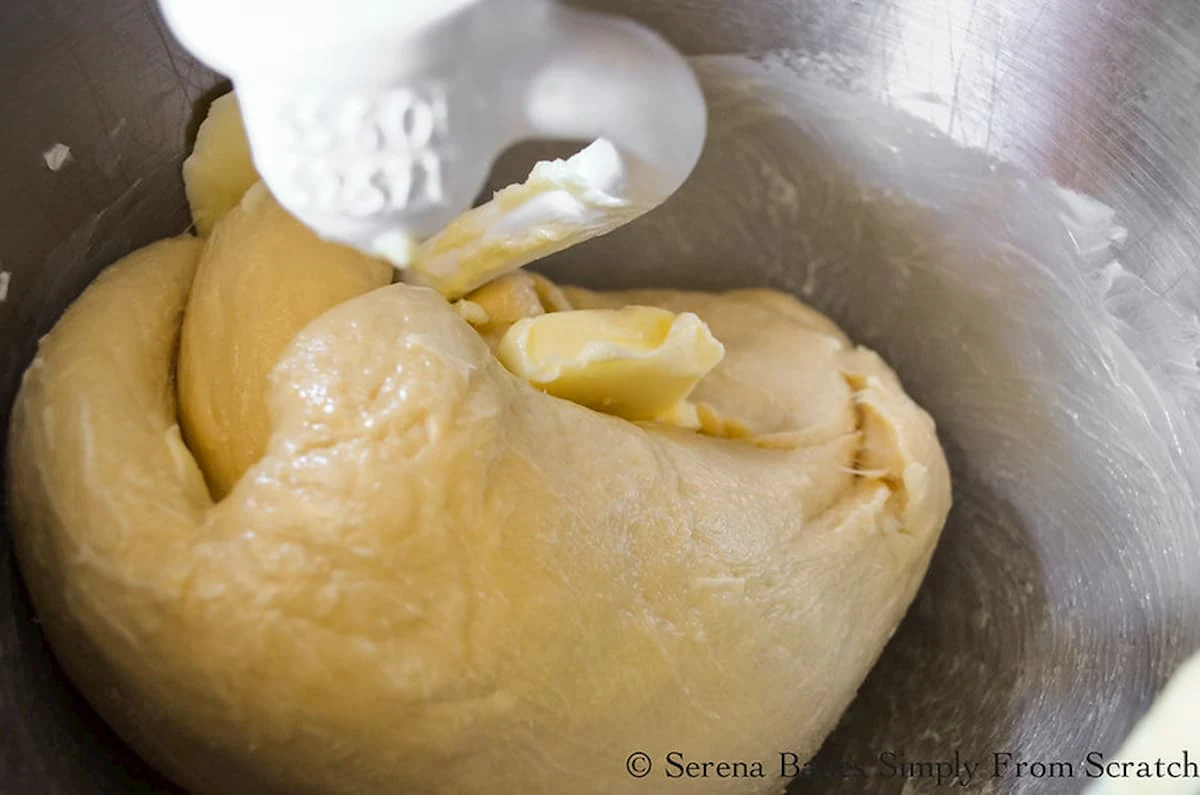 Blueberry Cinnamon Roll Dough with butter being kneaded in using a dough hook.
