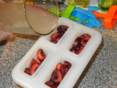 pouring juice into a popsicle mold with sliced cherries 