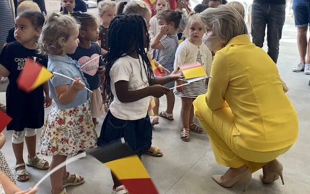 Queen Mathilde wore yellow silk shirt top and pants by Natan at primary school KAZ in Zottegem