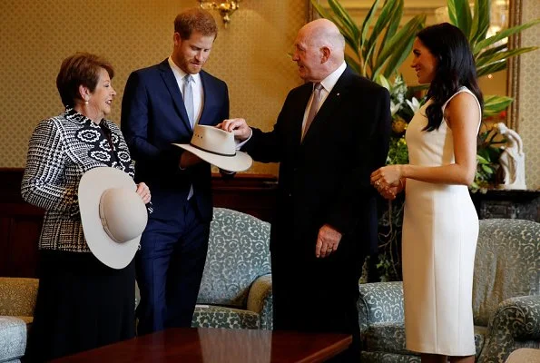 Meghan Markle wore a white Blessed dress by Australian designer Karen Gee, and she wore ​Stuart Weitzman suede pump in Haze Beige