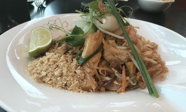 chicken pad Thai dish in a white bowl with a slice of lime