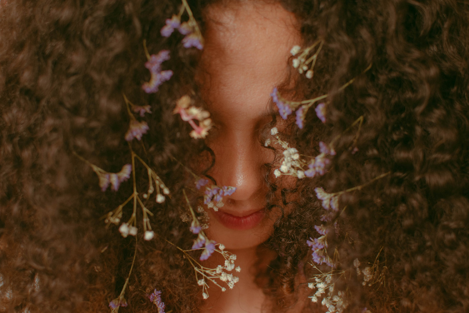 a close-up of curly hair with flowers in it